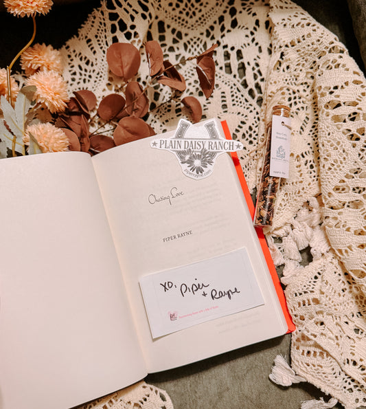 Book titled 'Chasing Love' by Piper Rayne on a decorative surface with flowers and cards.