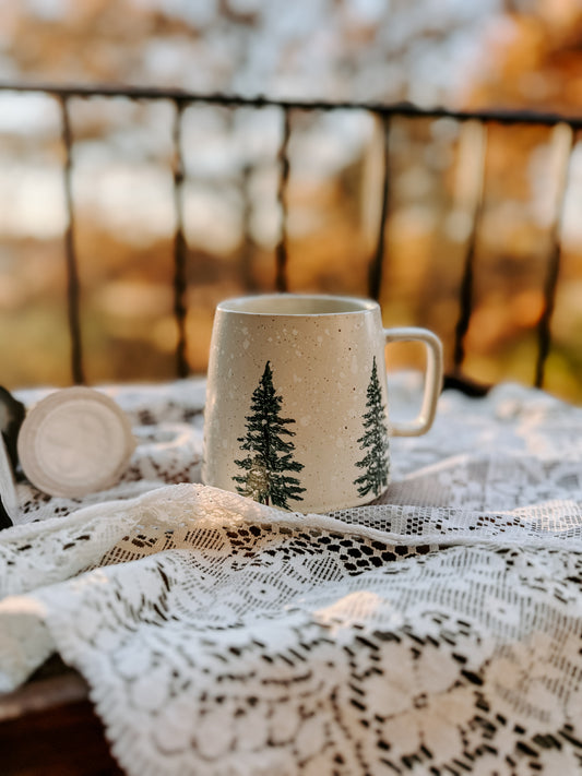 Ceramic mug with winter scene of trees and snow on a white background