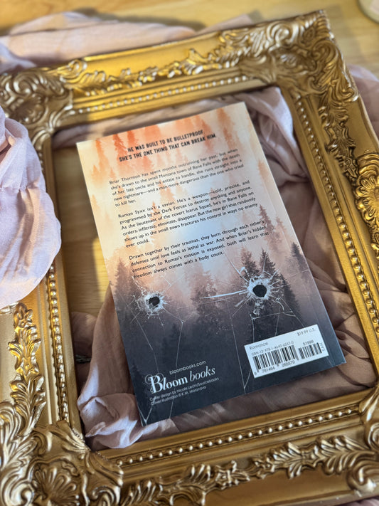 Book titled 'Bulletproof' by K.M. Moronova in a decorative gold frame.
