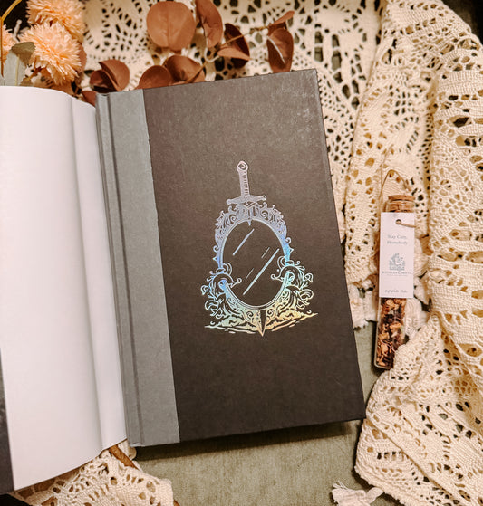 Book titled 'The Isle of Silver Sea' by Tasha Suri on a decorative background with flowers and lace.