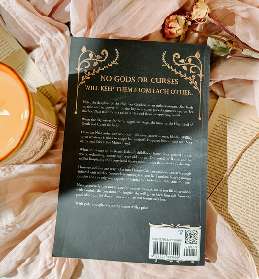 Book titled 'The Goddess of' by Randi Garner on a soft fabric background with a candle and flowers.