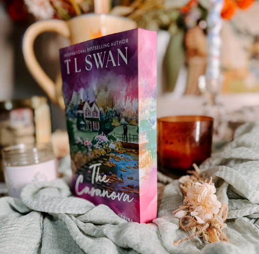 Book titled 'The Casanova' by TL Swan on a soft surface with candles and flowers.