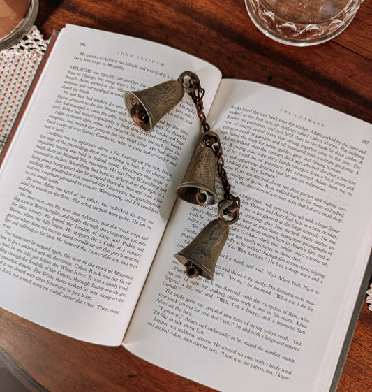 Open book with a vintage bell on a wooden surface