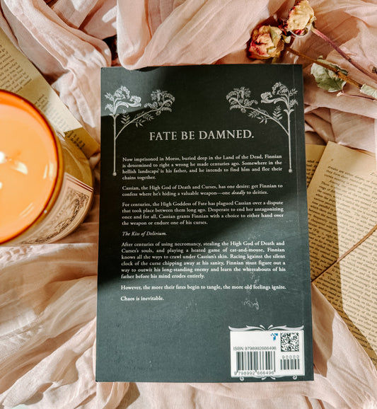 Book titled 'Even in Death' by Randi Garner on a soft fabric background with flowers and a candle.