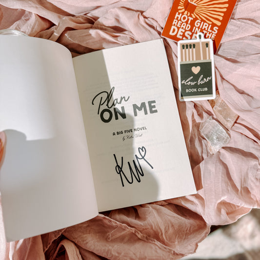 Book titled 'Plan On Me' by Katie West with decorative items on a textured surface