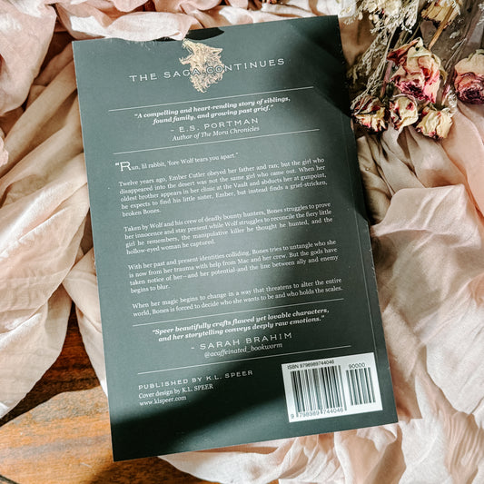 Book titled 'Fangs' by K.L. Speer on a soft fabric background with flowers.