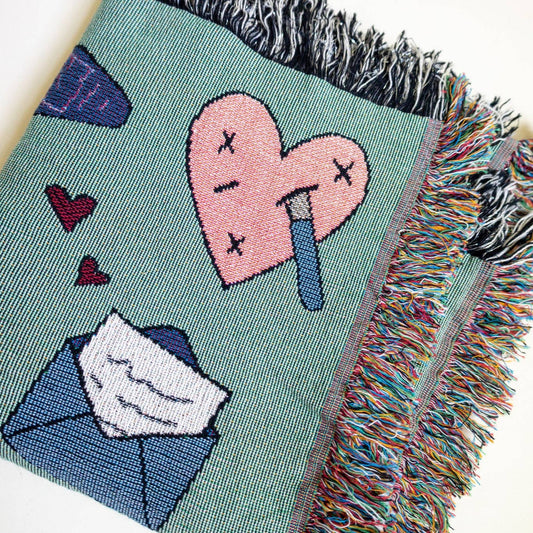 Decorative blanket with illustrations of a book, castle, and various objects on a light blue background. Book lover blanket