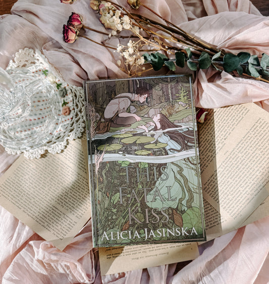 Book titled 'This Fatal Kiss' by Alicia Jasińska on an open book with floral and lace decorations.
