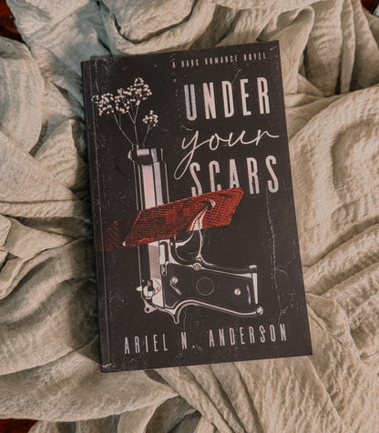Book titled 'Under Your Scars' by Ariel N. Anderson on a textured surface