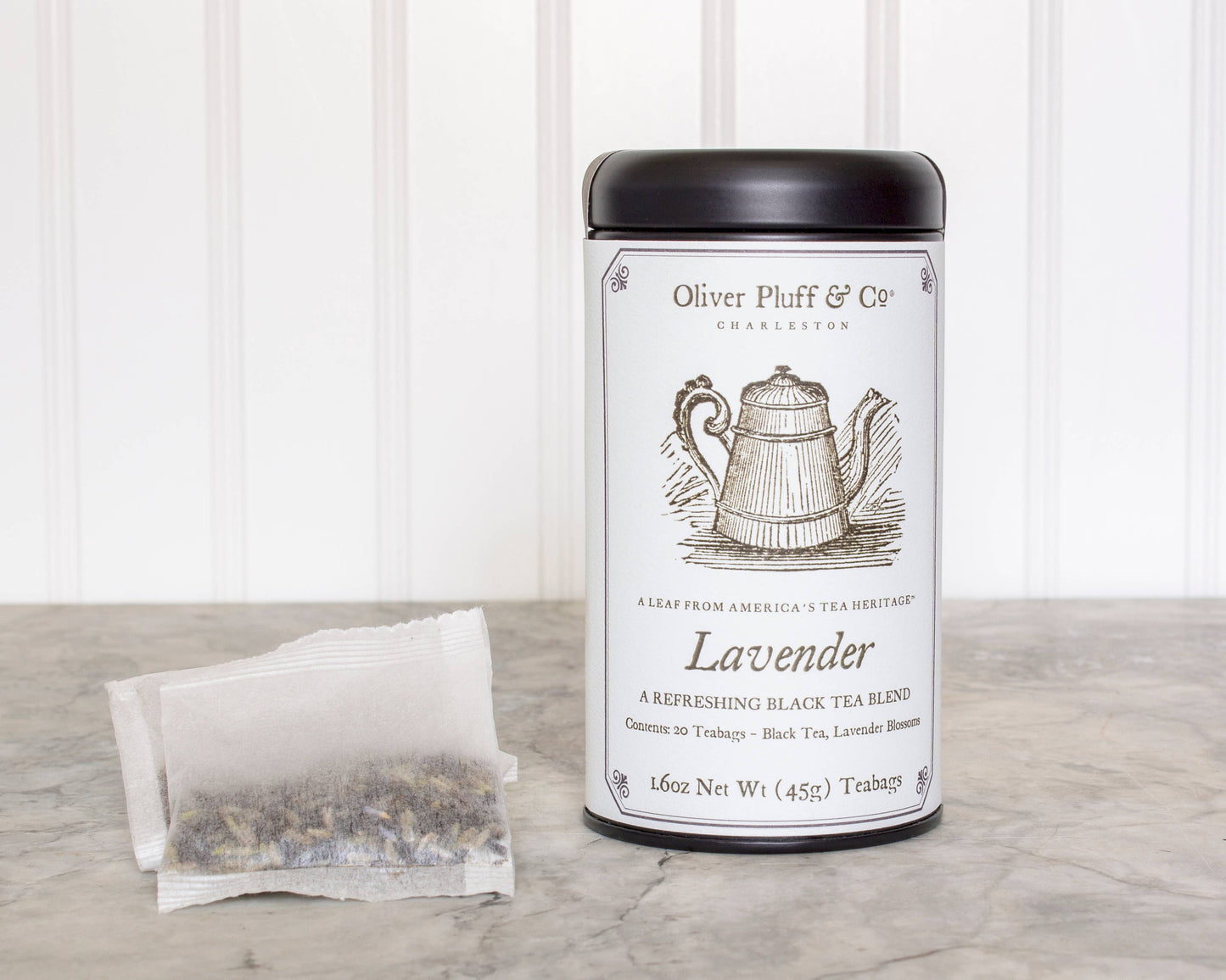 Tea canister labeled 'Oliver Pluff & Co' with a tea bag on a wooden surface. Lavender 