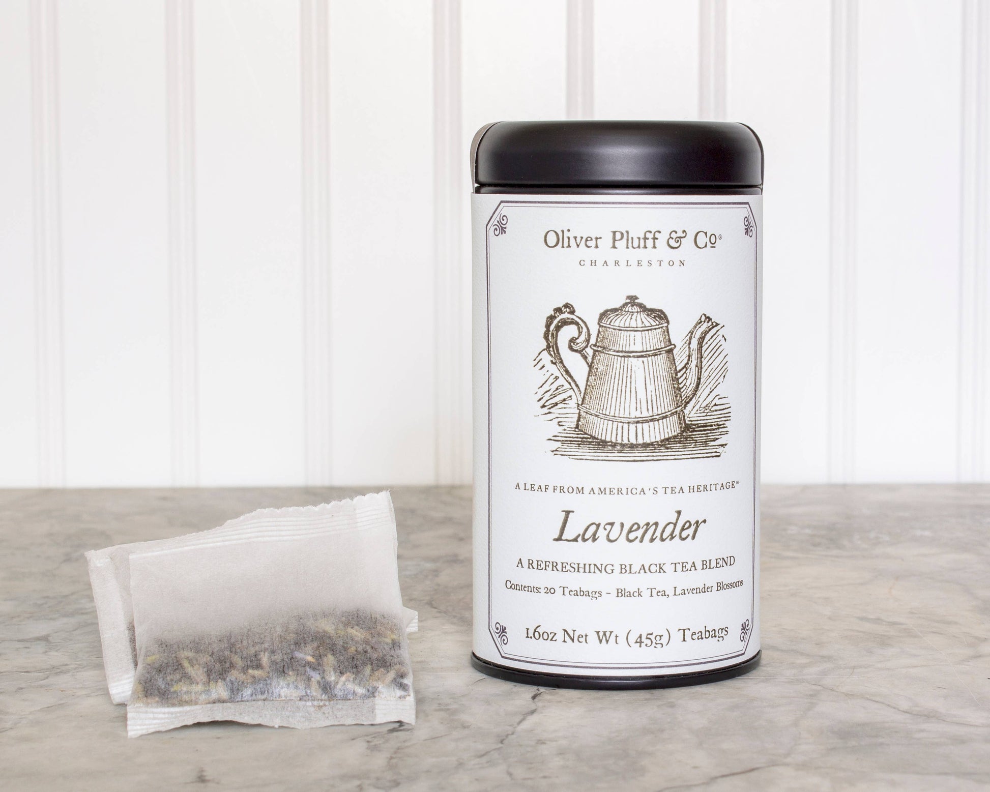 Tea canister labeled 'Oliver Pluff & Co' with a tea bag on a wooden surface. Lavender 
