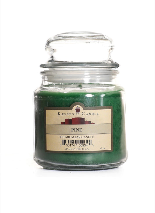 Green candle in a glass jar with a label on a white background roasted pine candle by keystone for with love Meena 