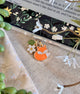 Fox charm on a clear pouch with floral design in the background dust plug charm 