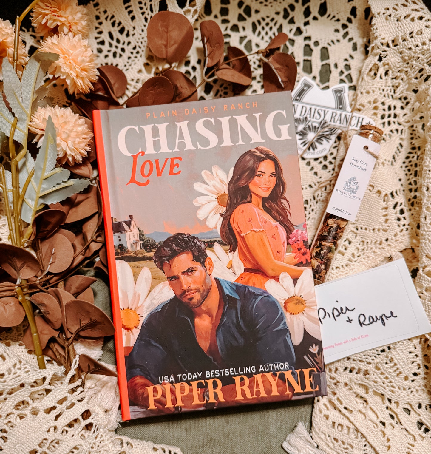 Book titled 'Chasing Love' by Piper Rayne on a decorative surface with flowers and cards.