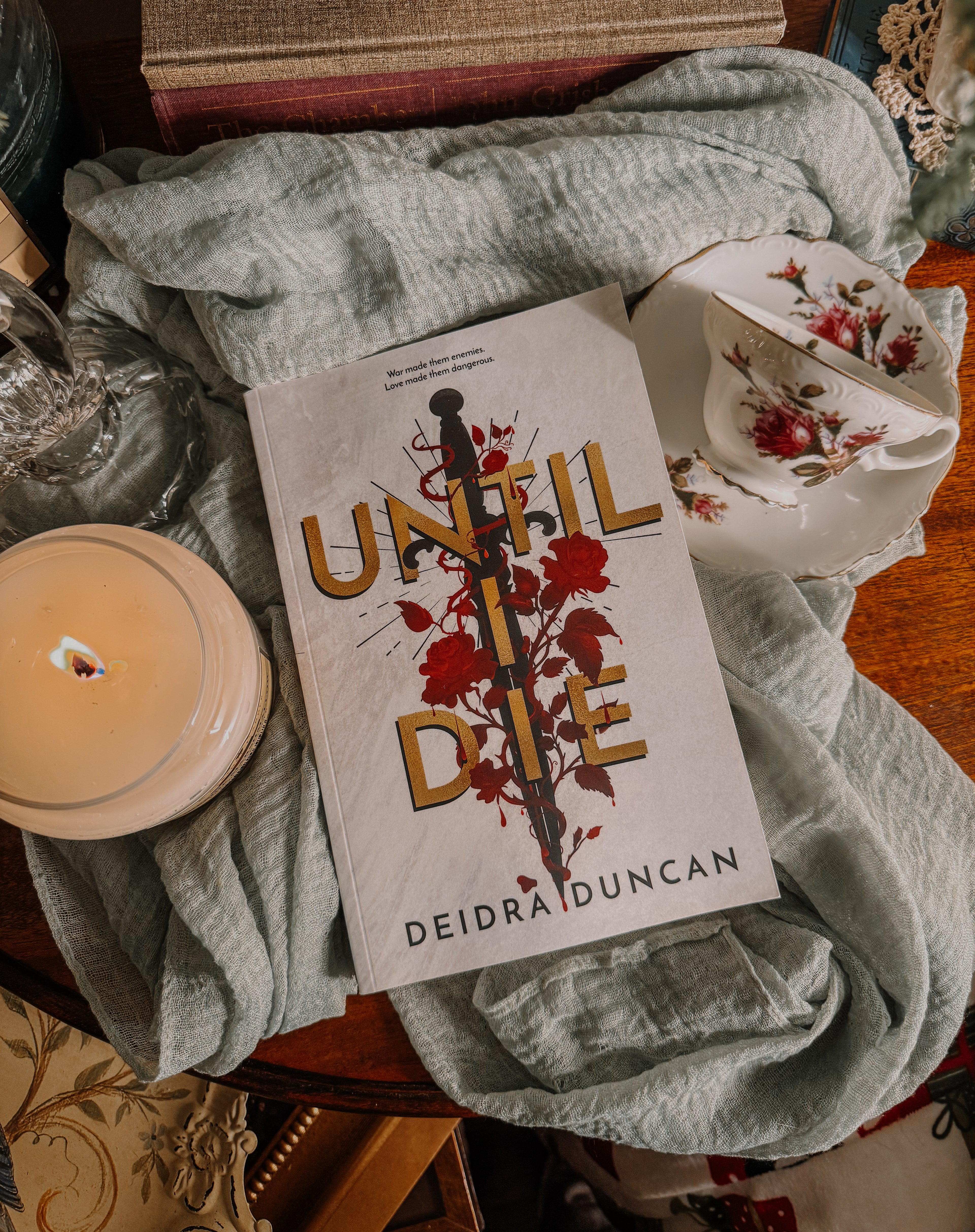 Book titled 'Until I Die' by Deidra Duncan on a textured surface with a candle and fabric.