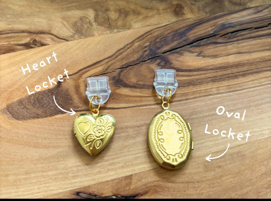 Gold heart-shaped earrings with clear clips on a wooden surface next to a Kindle device. Kindle dust plug 