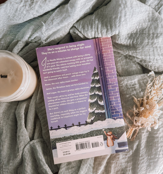 Book titled 'A Pack for Winter' by Eliana Lee on a textured surface with a candle and decorative elements.