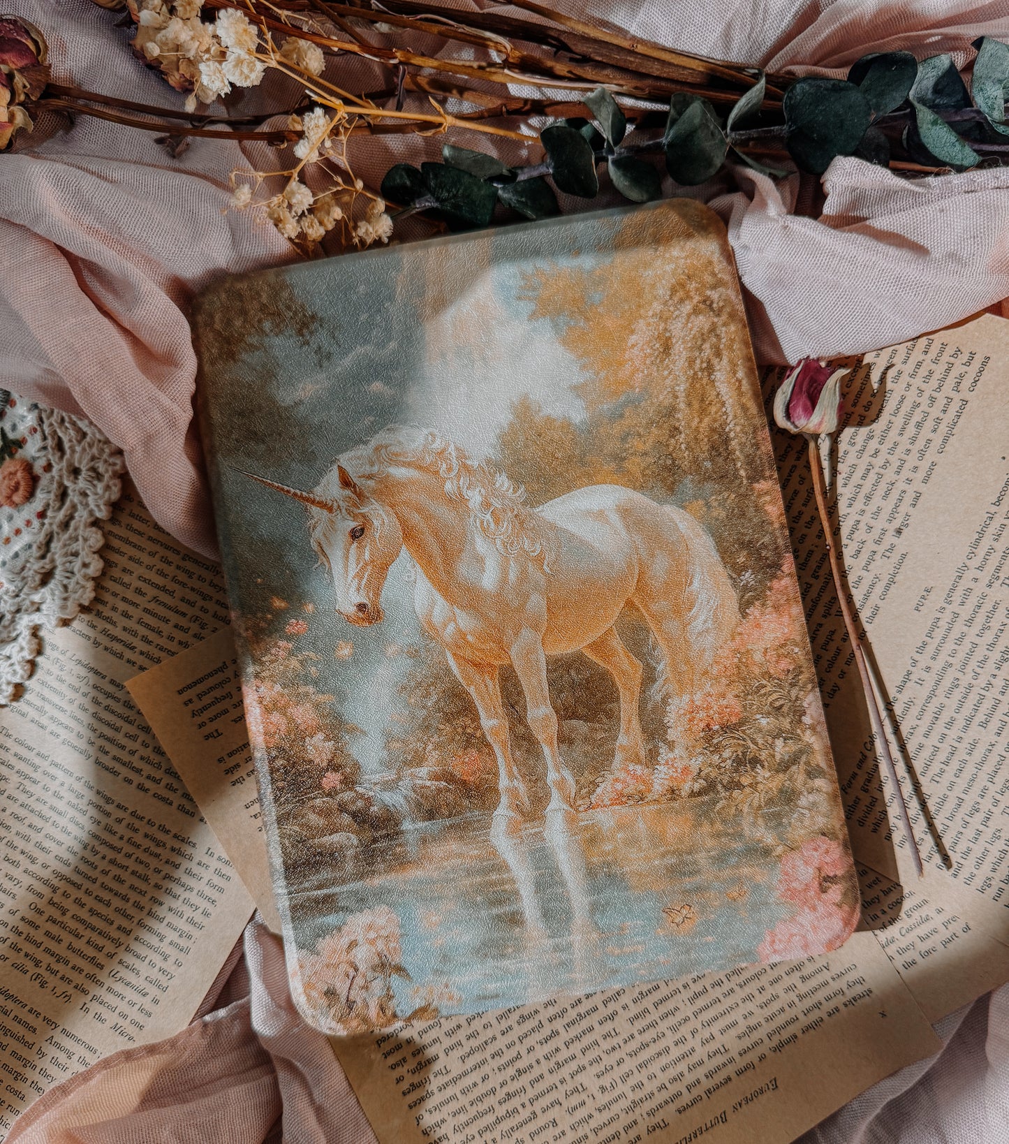 Kindle case  with a unicorn illustration on a surface with flowers and leaves