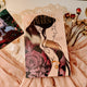 Book titled 'The Light Between' with fantasy-themed cover featuring two faces and floral elements, placed on a soft fabric background.