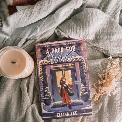 Book titled 'A Pack for Winter' by Eliana Lee on a textured surface with a candle and decorative elements.