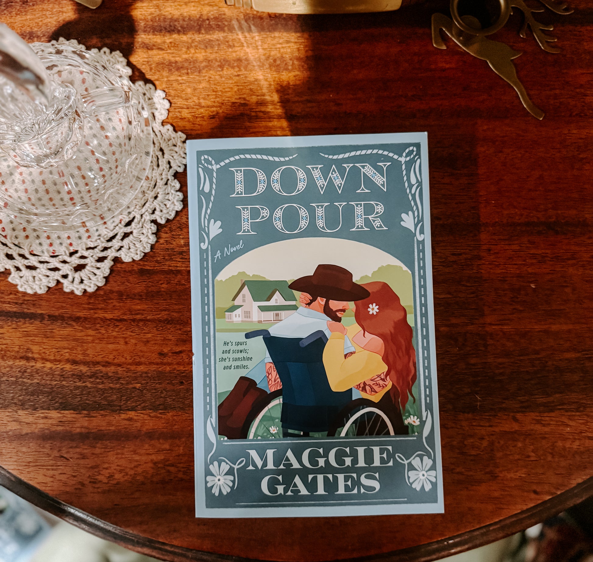 Book cover of 'Down Pour' by Maggie Gates on a wooden surface with decorative items.