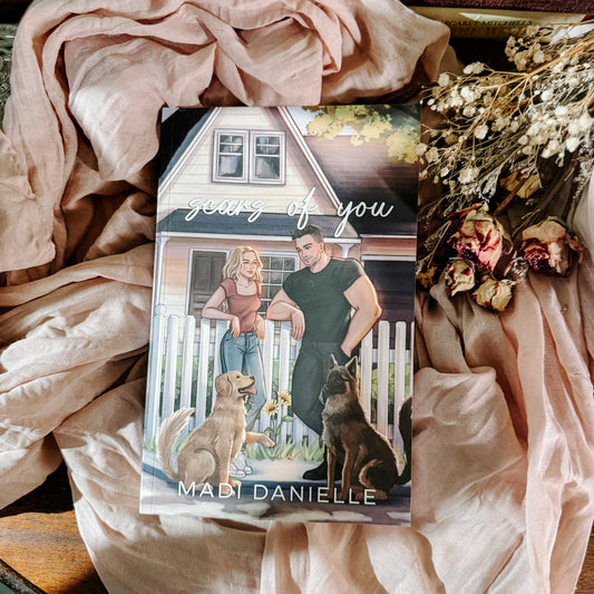 Book titled 'Years of You' by Madi Danielle with a couple and dogs on the cover, surrounded by pink fabric and flowers.