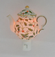 Decorative teapot night light with floral design on a plain background
