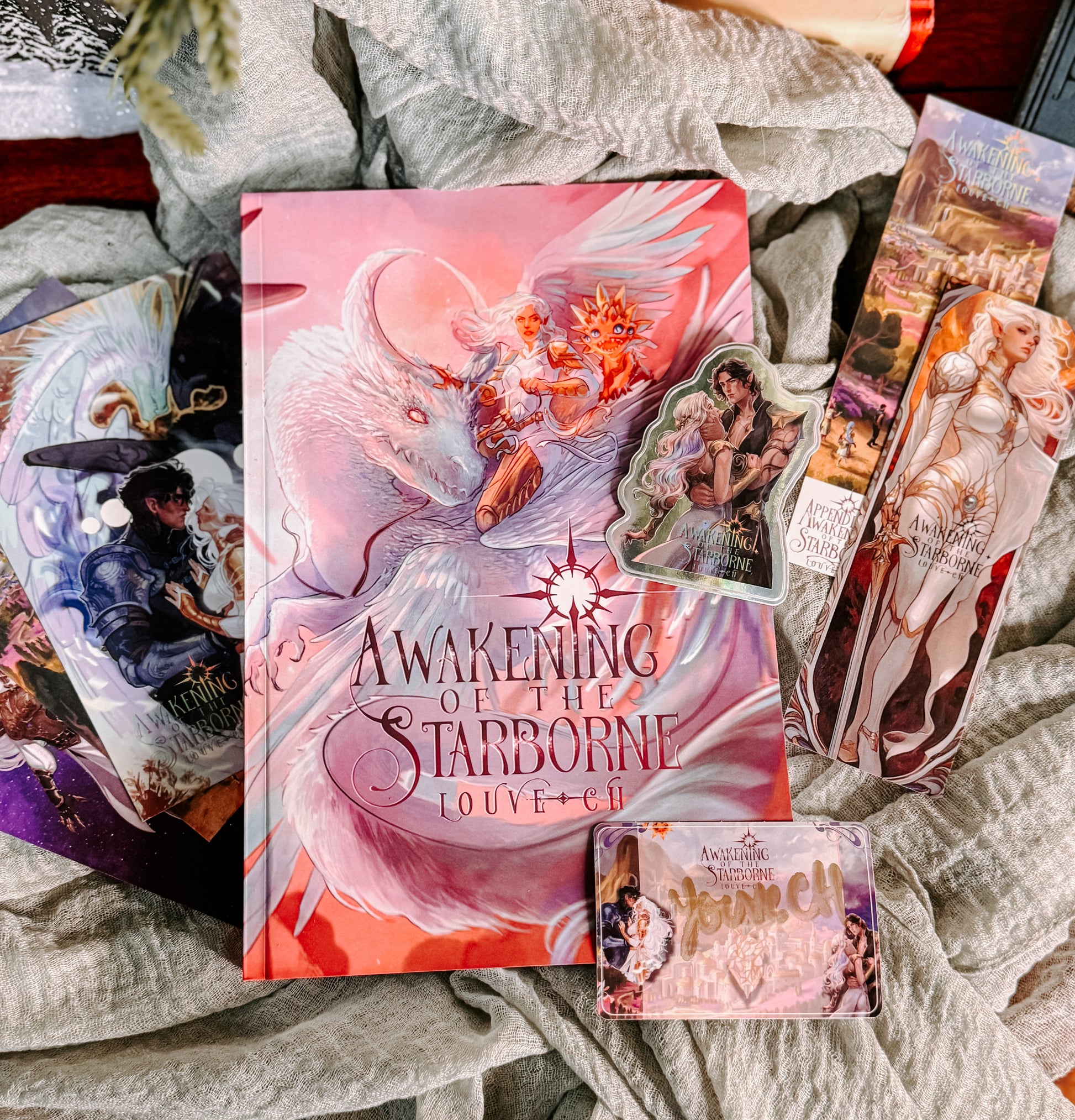 Collection of 'Awakening of the Starborne' book and related merchandise on a textured surface.