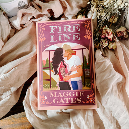 Book titled 'Fire Line' by Maggie Gates on a soft fabric background with flowers.