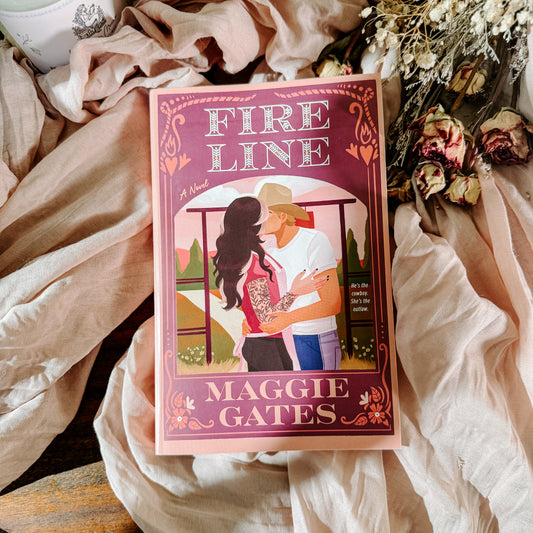 Book titled 'Fire Line' by Maggie Gates on a soft fabric background with flowers.