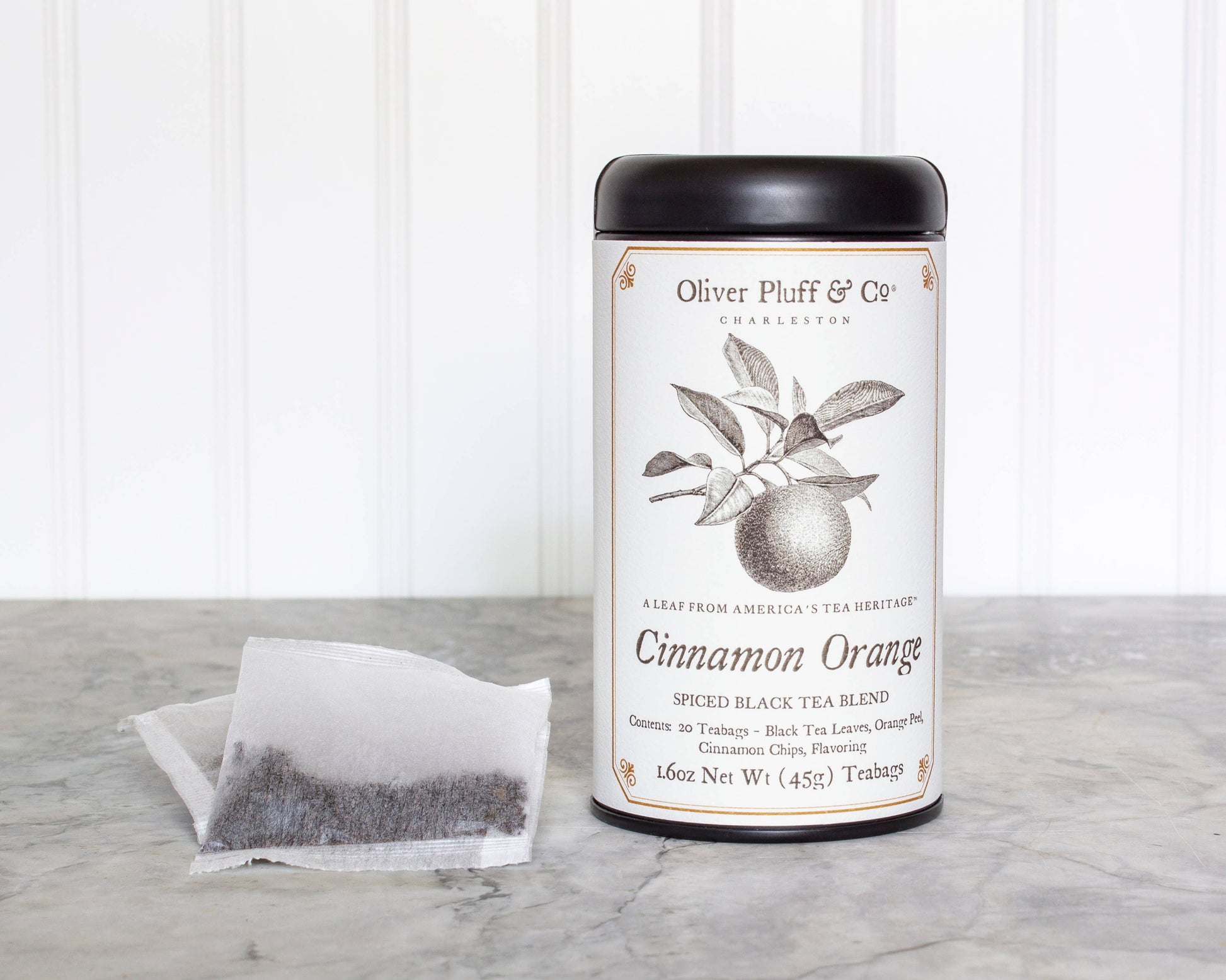 Tea canister labeled 'Cinnamon Orange' by Oliver Pluff & Co on a marble surface with a white background.
