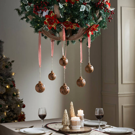 Decorative Christmas wreath with ornaments hanging over a table set for dinner.