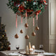 Decorative Christmas wreath with ornaments hanging over a table set for dinner.