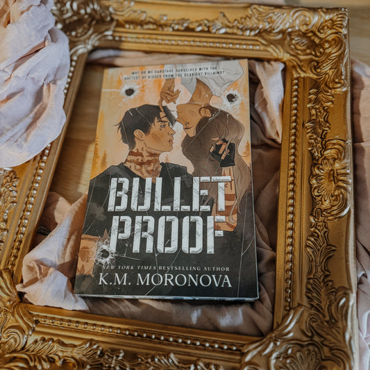 Book titled 'Bulletproof' by K.M. Moronova in a decorative gold frame.