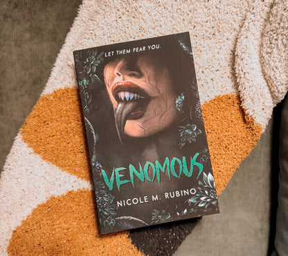 Book titled 'Venomous' by Nicole M. Rubino on a textured surface