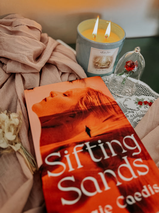 Book titled 'Sifting Sands' by Angie Caedis on a soft fabric background