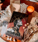 Book titled 'Silent Sorrows' by A.G. Harris on a wooden surface with a candle and decorative items.