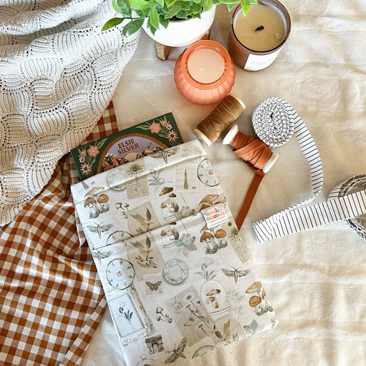 Flat lay of stationery items including a notebook, candles, and a plant on a textured surface. Book sleeve 