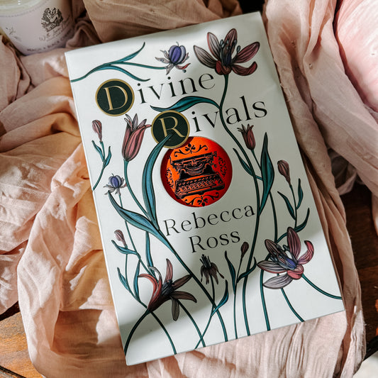 Book titled 'Divine Rivals' by Rebecca Ross with floral design on a soft fabric background