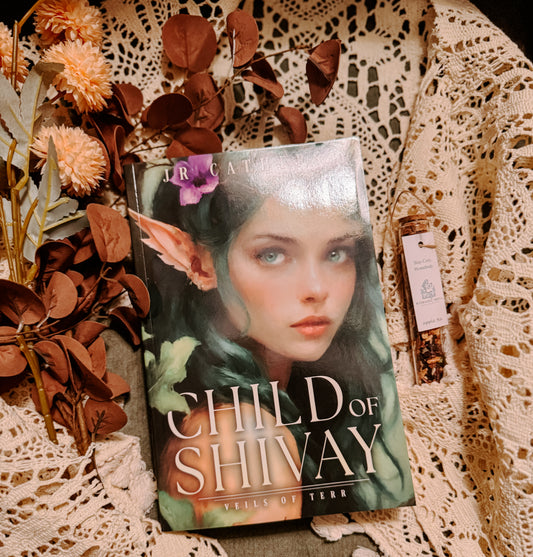 Book titled 'Child of Shivay' with a fantasy cover featuring an elf-like character, placed on a textured surface with flowers and leaves.