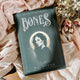 Book titled 'Bones' by K.L. Speer on a soft fabric background with flowers.