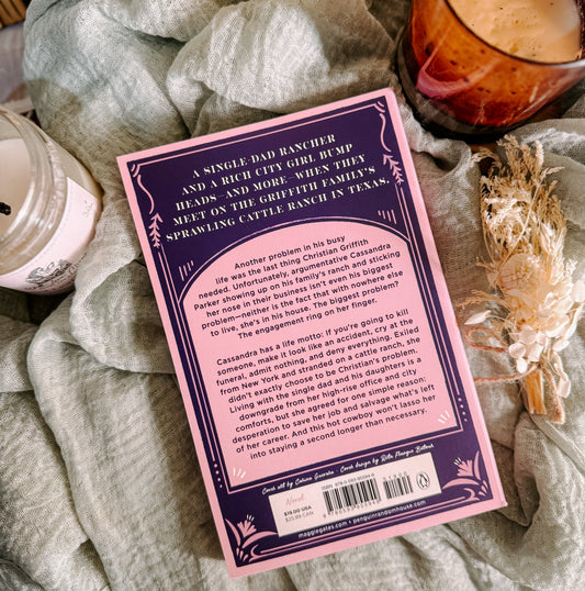 Book titled 'Dust Storm' by Maggie Gates on a textured surface with a candle and decorative elements.