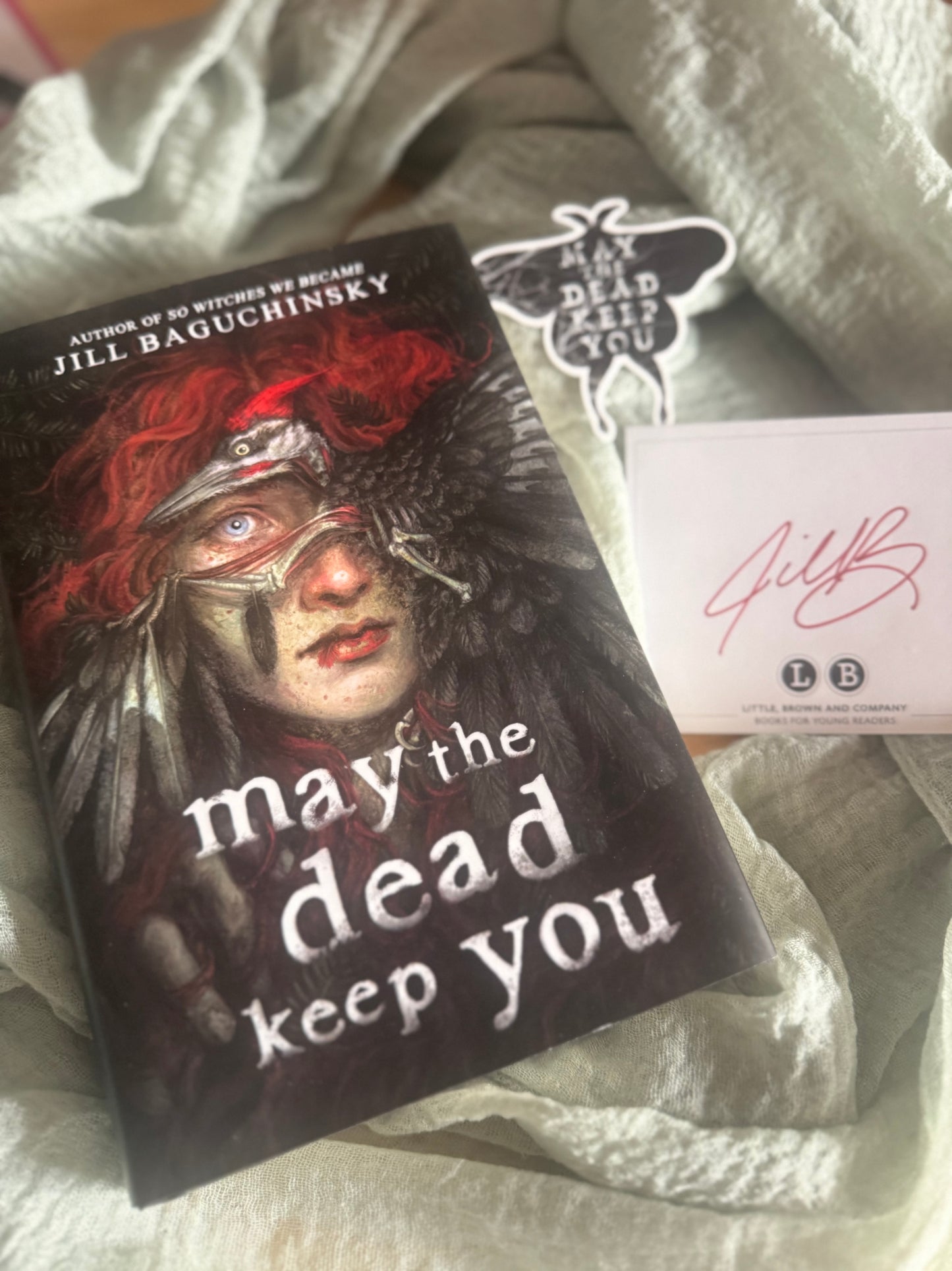 Book titled 'May the Dead Keep You' by Jill Baguchiinsky on a textured surface.