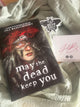Book titled 'May the Dead Keep You' by Jill Baguchiinsky on a textured surface.
