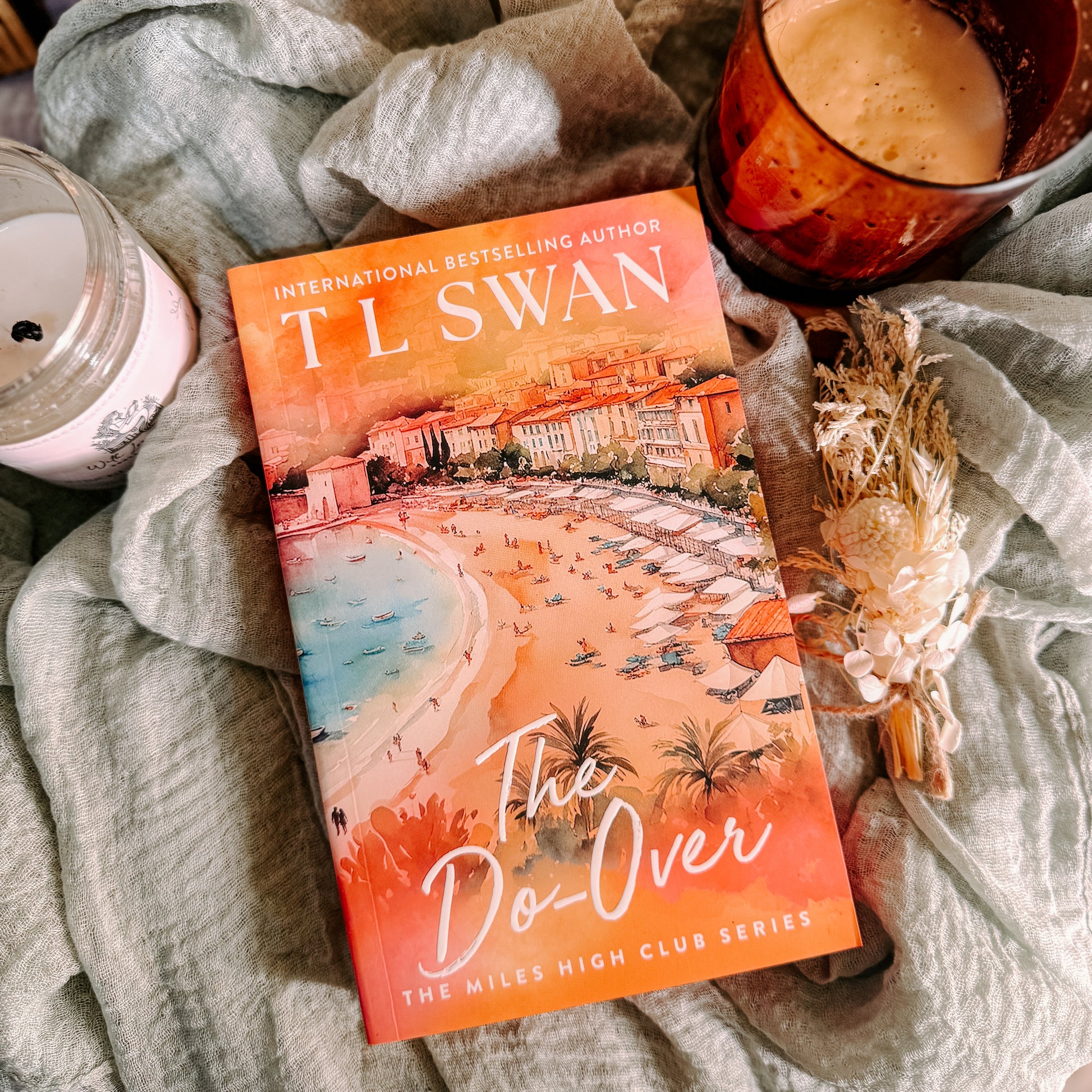 Book titled 'The Do-Over' by T.L. Swan on a soft surface with a candle and cup.