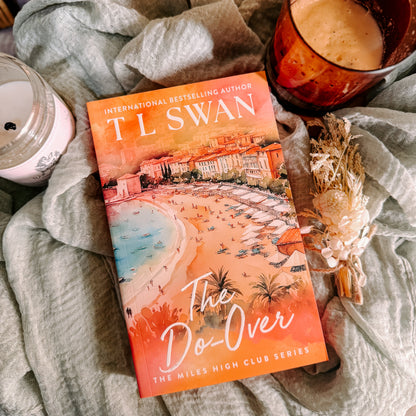 Book titled 'The Do-Over' by T.L. Swan on a soft surface with a candle and cup.