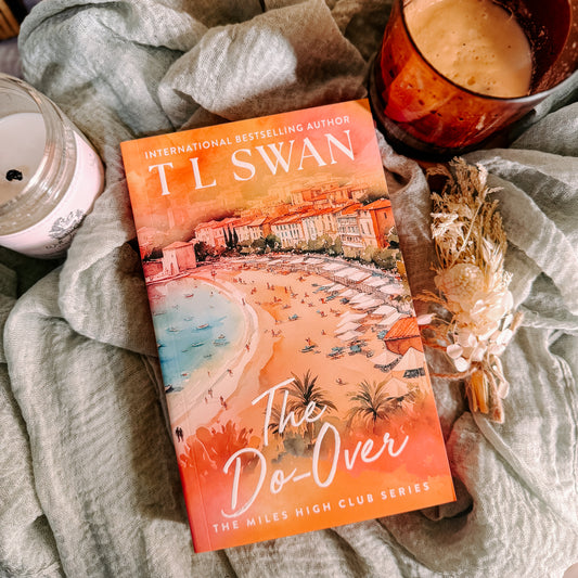 Book titled 'The Do-Over' by T.L. Swan on a soft surface with a candle and cup.