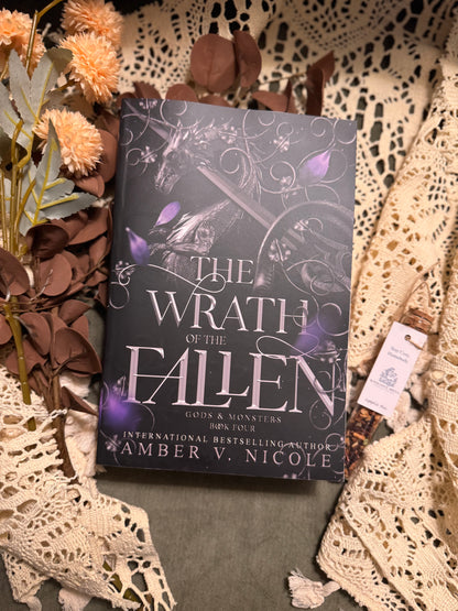 Book titled 'The Wrath of the Fallen' by Amber V. Nicole on a textured surface with decorative elements.