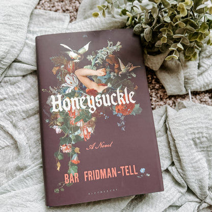 Book titled 'Honeysuckle' by Bar Fridman-Tell on a textured surface with plants.