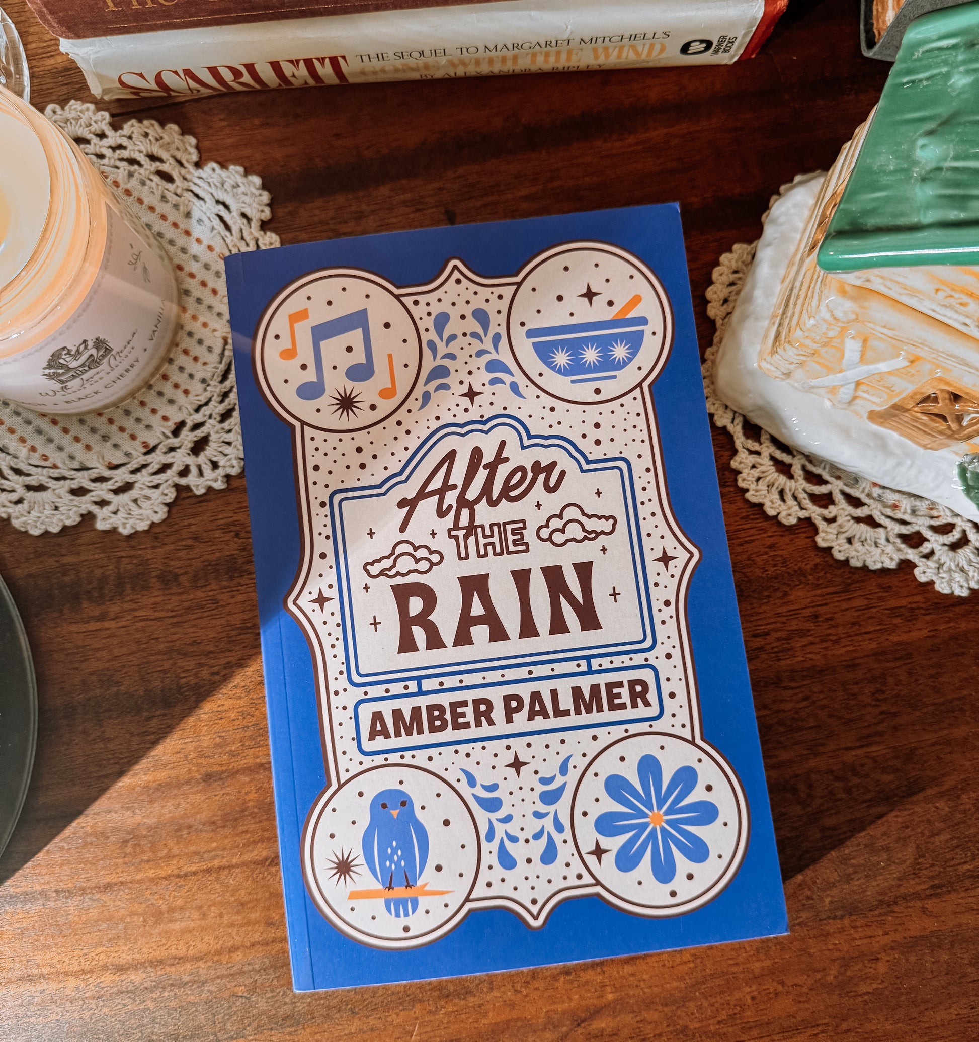 Book titled 'After the Rain' by Amber Palmer on a wooden surface with decorative elements.